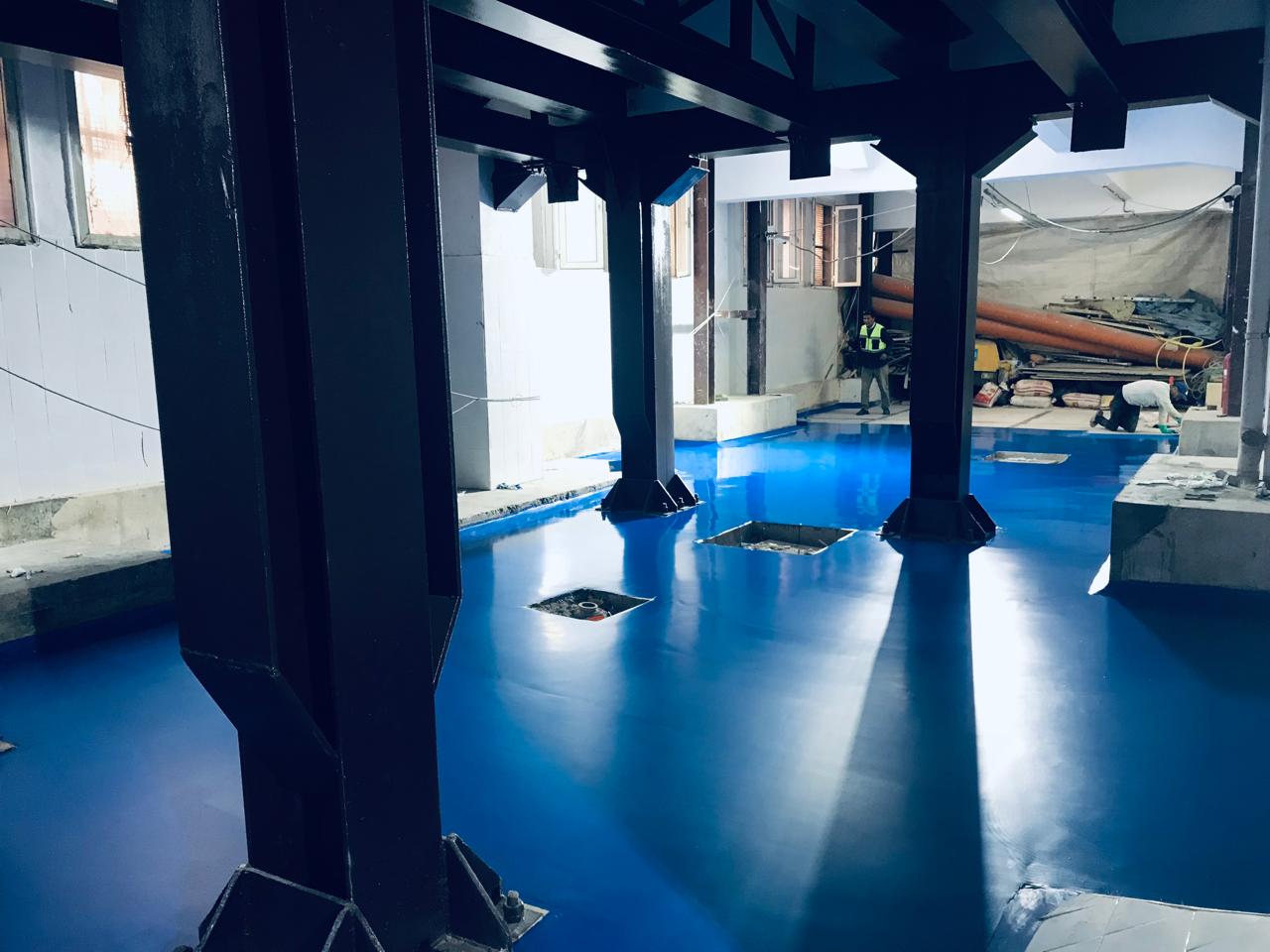 Application d'une résine bleue autolissante sur un chantier industriel
